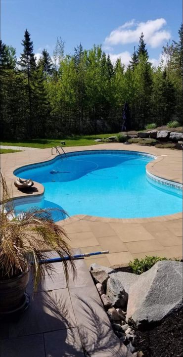 Inground pool with landscaping and rocks in yard