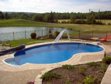 Inground pool with slide, fenced in backyard