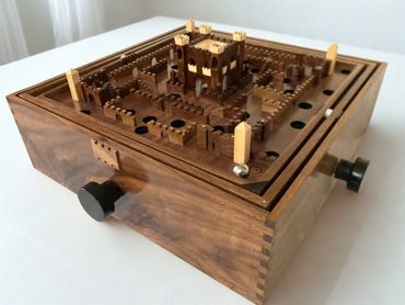 Wooden labyrinth maze game with castle design and metal ball.