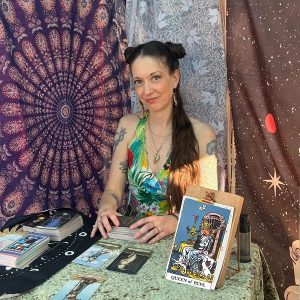 A woman with tattoos doing a tarot card reading.