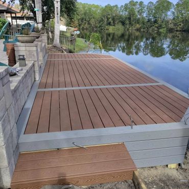 A wooden dock extends over a calm lake with surrounding trees.