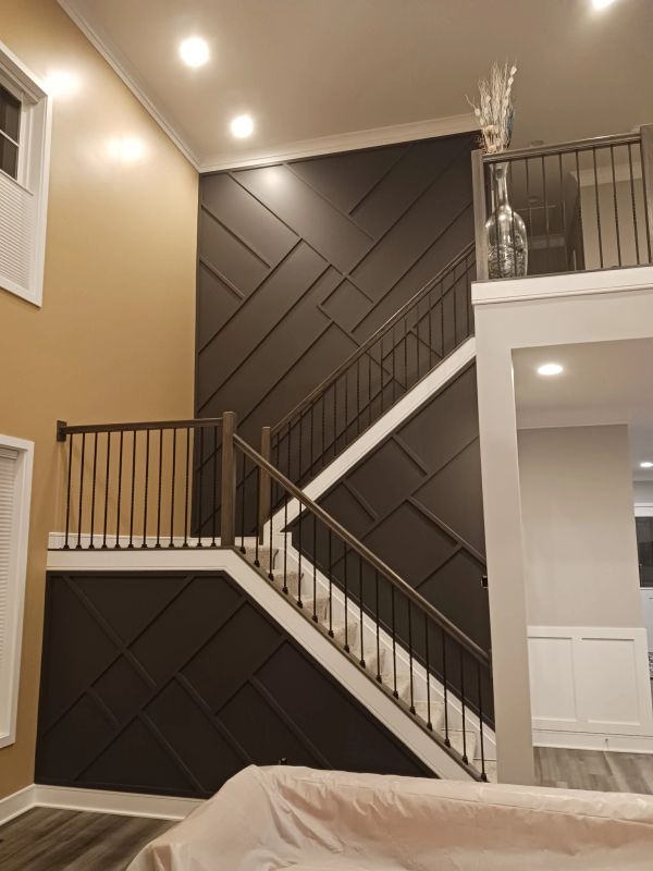 Modern staircase with stylish dark geometric wall panels and warm lighting.