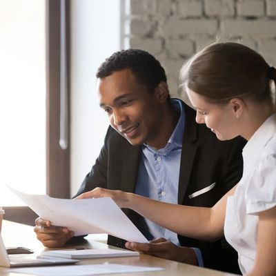 Two colleagues reviewing documents together in an office setting.
