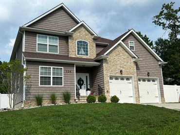 Modern two-story house with stone and shingle exterior and double garage doors.