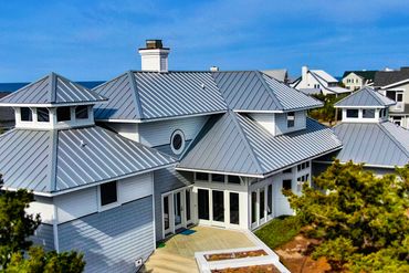 Modern coastal house with metal roofs and large windows.