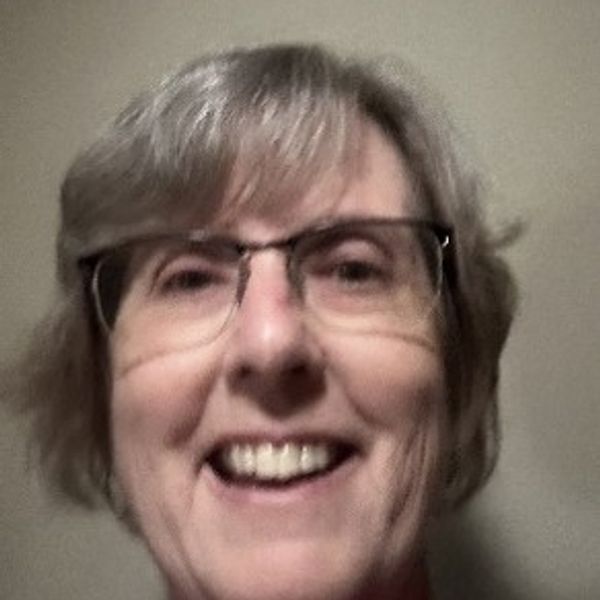 Smiling woman with glasses and short gray hair.