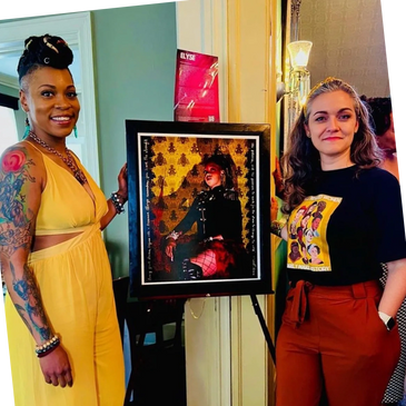 Portrait representing a black woman. The artist is standing next to it with the model