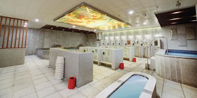 Public showers & baths in spacious room & premium grey tile, for a luxury spa & sauna experience