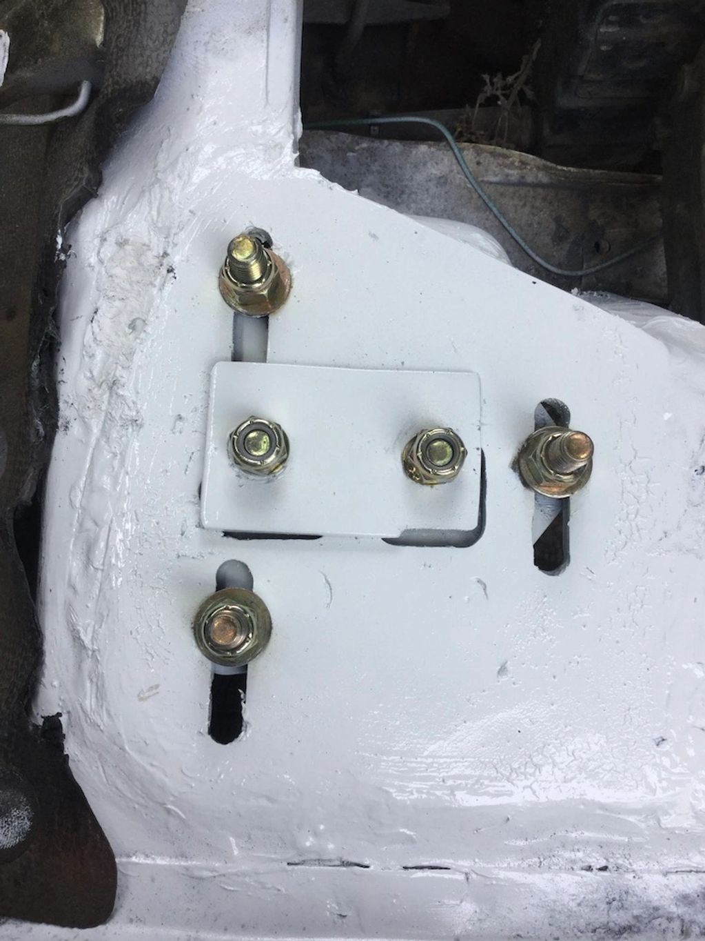 Close-up of a white-painted metal plate with bolts and nuts.