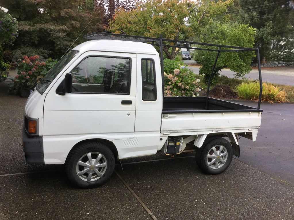 Small white utility truck with a metal frame on the back.