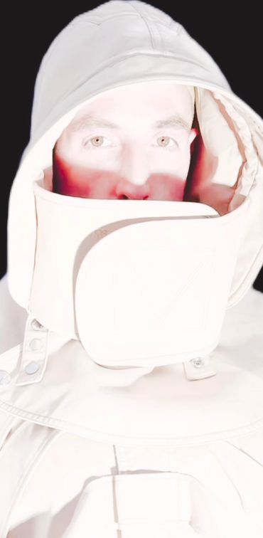 Person in a bright white hooded jacket with face partially covered, contrasting against a black background.