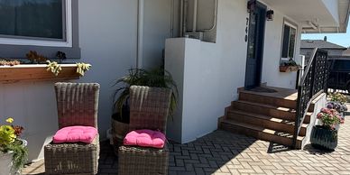 Outdoor patio area with wicker chairs and pink cushions.