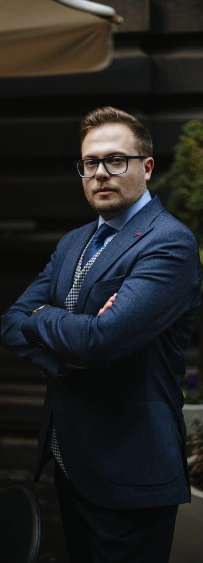 Confident man in a suit and glasses with arms crossed.