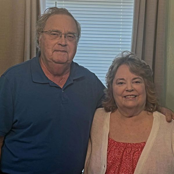 Elderly couple posing indoors in front of a window.