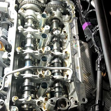 Engine Repair. Cylinder Head Cover Removed with Engine Timing and Valvetrain Components Visible.