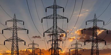 Electricity pylons silhouetted against a sunset sky.