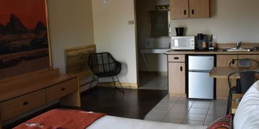 Cozy hotel room with bed, kitchenette, and seating area.