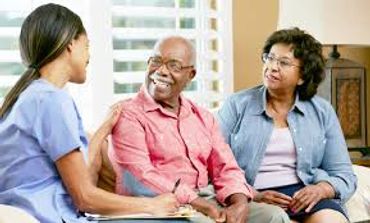 Caregiver talks with elderly couple during a home visit.