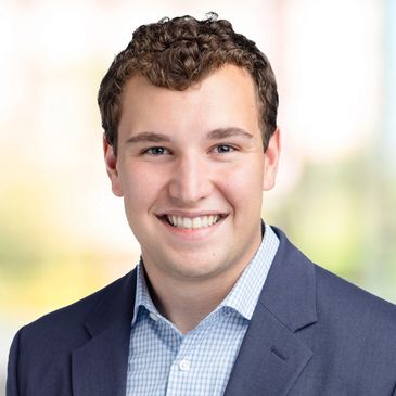 Young man in a suit smiling with a blurred background.