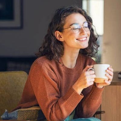 Woman enjoying a warm drink with a smile.