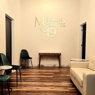 Minimalist salon waiting area with green chairs and a white couch.