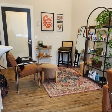 Cozy, stylish waiting area with chairs, plants, and decorative shelving.