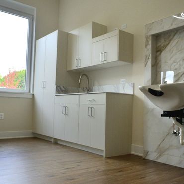 Bright room with white cabinets, marble accents, and a wall-mounted sink.