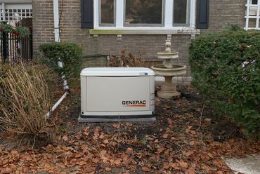 Generac standby generator installed in a garden area near a house.