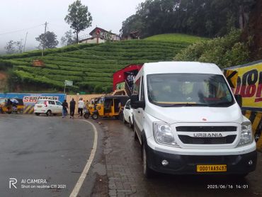 White Force Urbania van and autos by a tea estate on a foggy day.