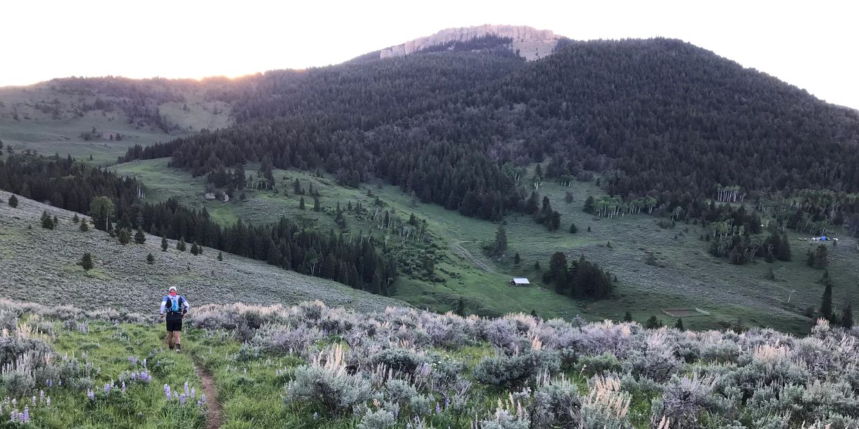 Person hiking on a trail in a mountain landscape.