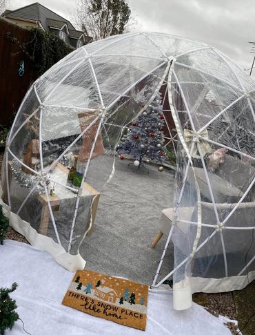 Christmas themed movie night igloo, with Christmas tree, sofas and projector screen.