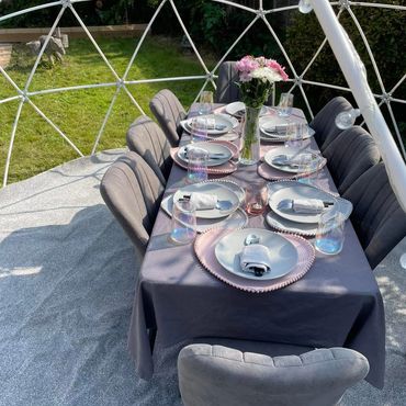 Group dining set up for 8 guests with flowers in a vase as table decor.