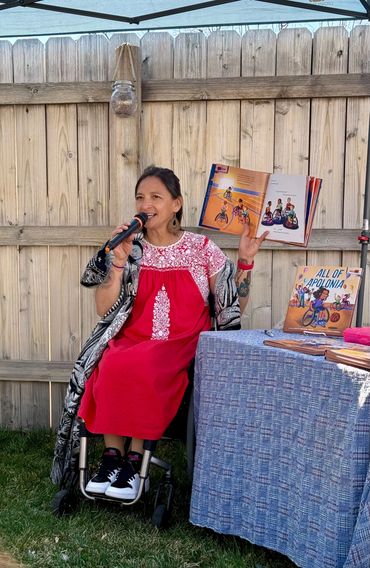 Patty in red dress holding book and mic