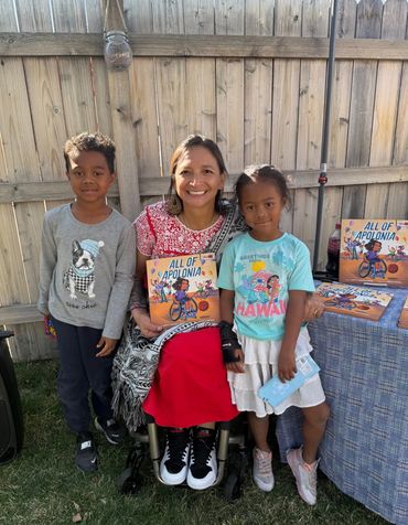 Patty and two kids posing for a picture and holding All of Apolonia