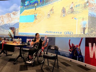 Patty reading from book with big screen in background