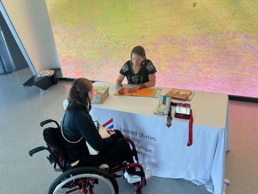 Patty signing a book for a person in a wheelchair