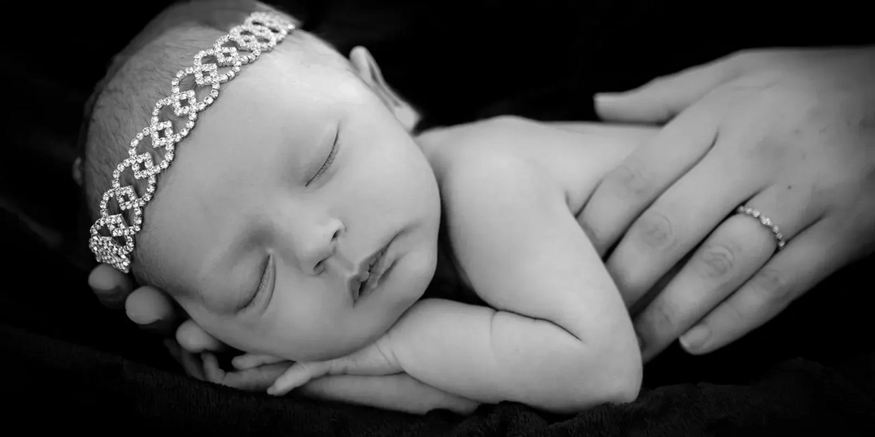 Black & White close up portrait of a sleeping baby girl resting in her mothers hands. Charleston Ne