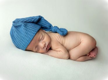Fine Art Portrait Editorial Vibe Charleston SC. Tiny Newborn in blue hat on cream backdrop