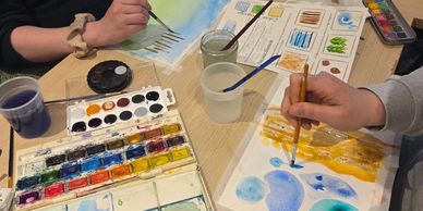 Two people painting with watercolors at a table.