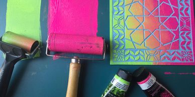 Printing supplies with pink paint and a stencil.