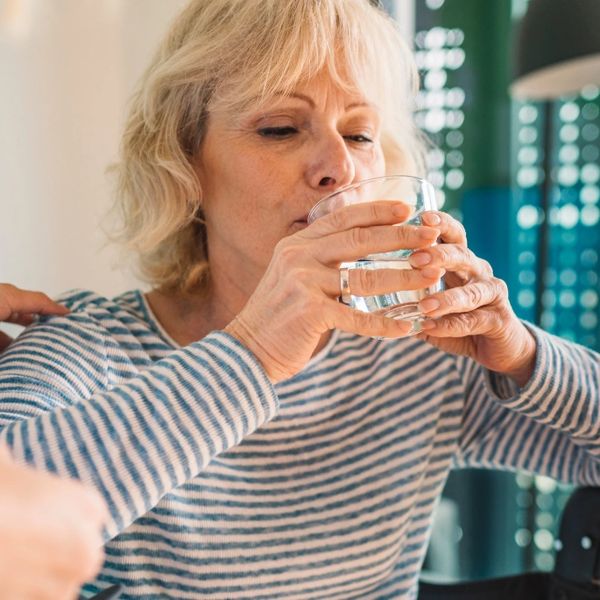 A woman drinking thickened water.