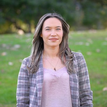 Woman posing outdoors with a soft smile.