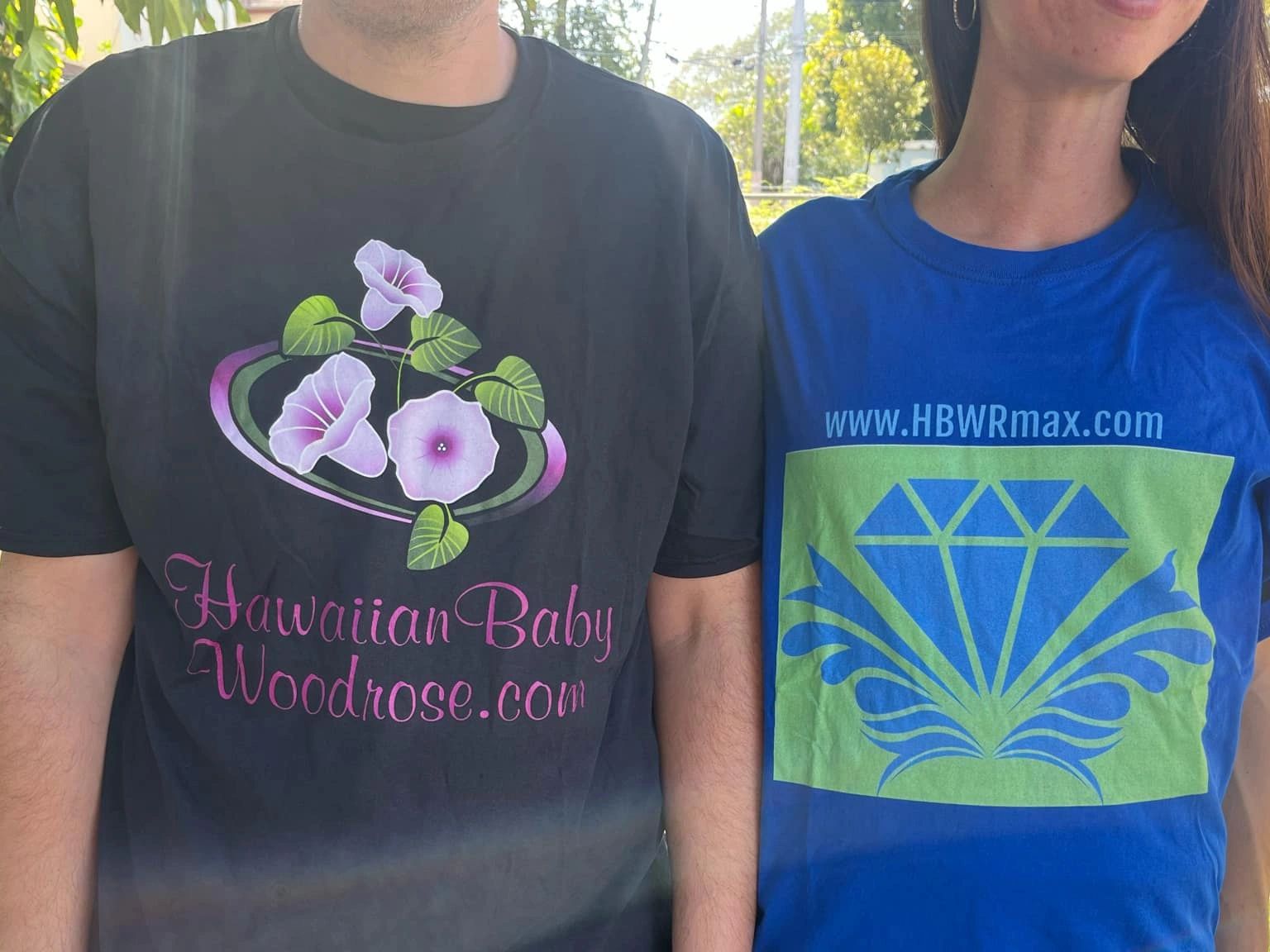 Two people wearing promotional T-shirts outdoors in sunlight.