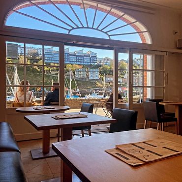 Cozy interior of a cafe with a harbor view through large windows.