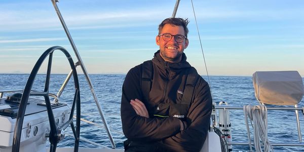 Man smiling on a boat with the ocean in the background.