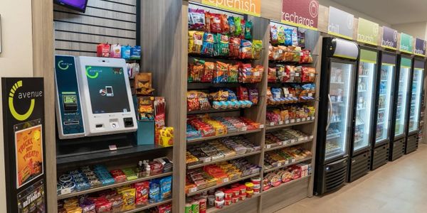 Convenience store snack and drink aisle with self-checkout kiosk.