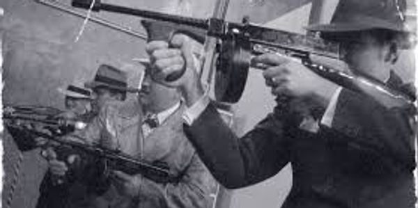 Four men in fedoras and trench coats with 1930s machine guns