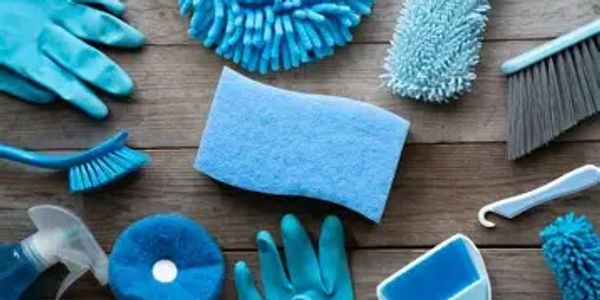 Various blue cleaning tools and gloves arranged on a wooden surface.