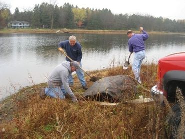 Del Kramer (kneeling), Erchal Springer (left) and Dennis Fruetel (right) prepare a rock for removal