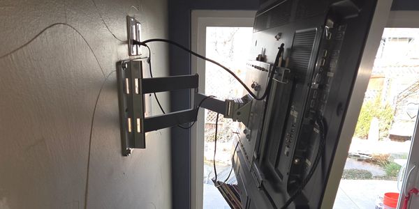 Television mounted on a wall with cables connected.
